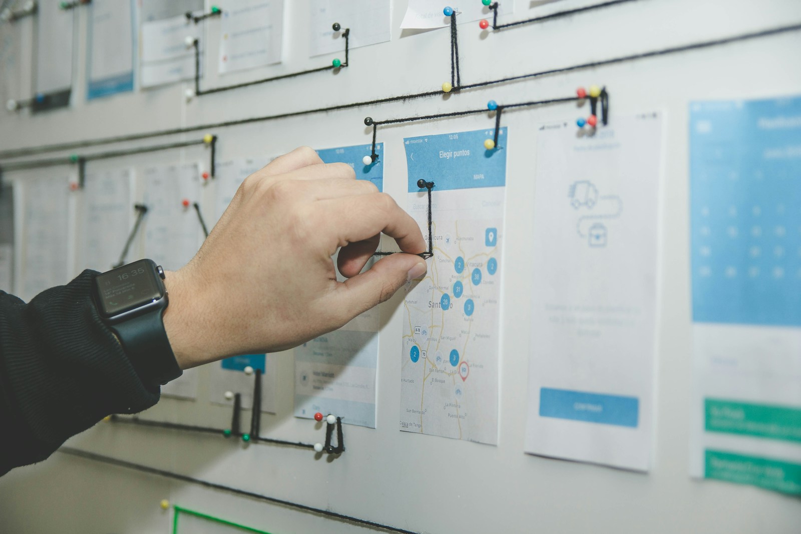 Process flows pinned to a wall, one hand moving a card